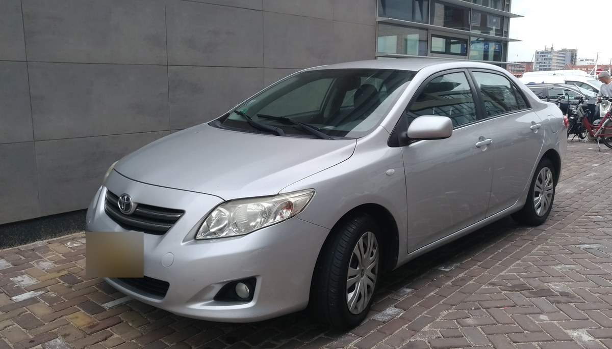 Серебристая Toyota Corolla E150 седан, вид спереди в три четверти