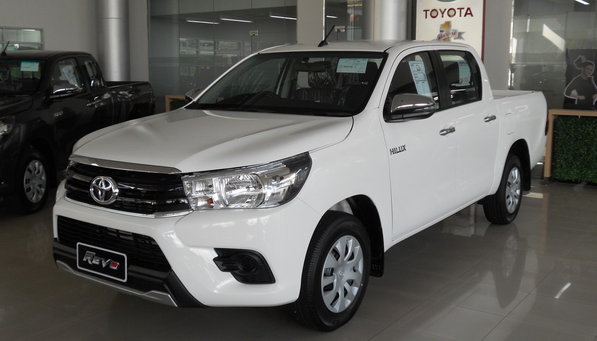 Белый Toyota Hilux с двойной кабиной в автосалоне, вид спереди в три четверти