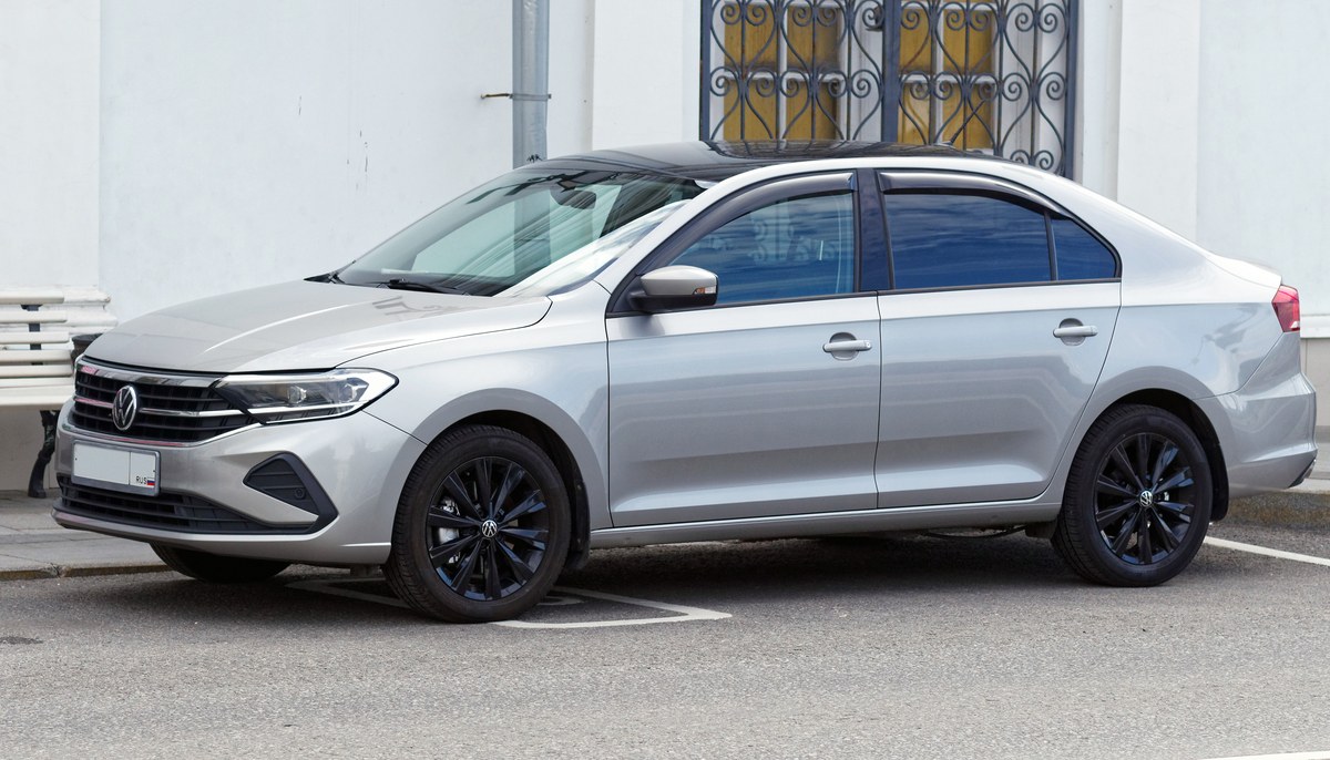 Серебристый Volkswagen Polo лифтбек 2020 года, вид спереди сбоку, стоит у здания на парковке