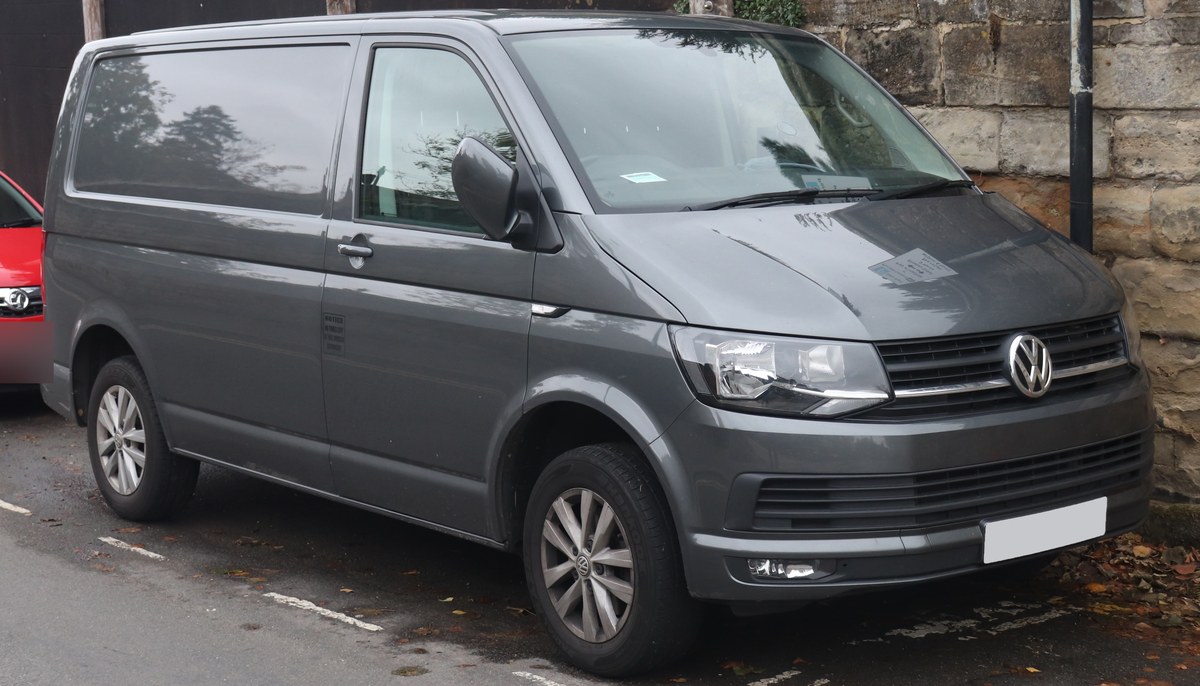 Серый Volkswagen Transporter T6 в кузове фургон, вид спереди в три четверти на городской улице